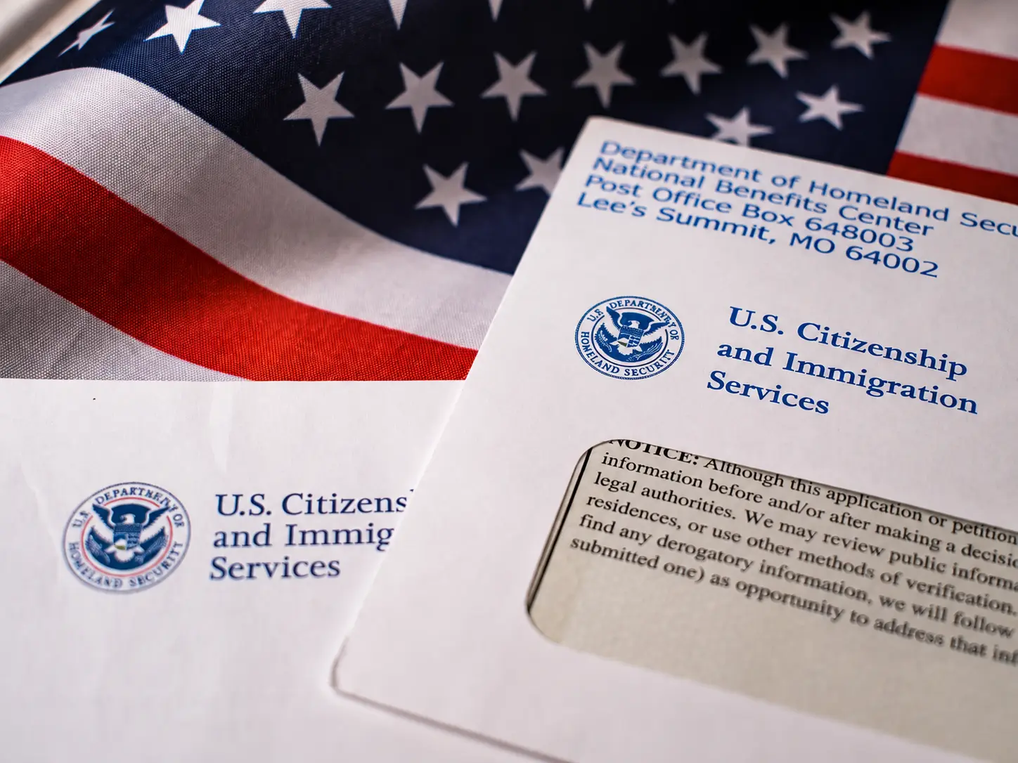 Documentos de USCIS junto a una bandera de Estados Unidos
